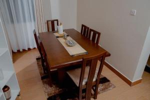 a wooden dining room table with chairs and a candle on it at Broadbills Haven apartment in Kampala +5 photos