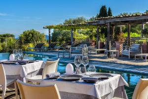 ein Restaurant mit Tischen und Stühlen neben einem Pool in der Unterkunft Les Bergeries De Palombaggia in Porto-Vecchio