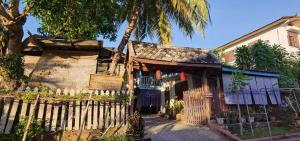 ein altes Haus mit einem Zaun davor in der Unterkunft Khonesavane Hostel in Luang Prabang