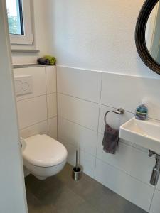 La salle de bains blanche est pourvue de toilettes et d'un lavabo. dans l'établissement Ruheoase mitten in der Natur, à Wilhelmsdorf
