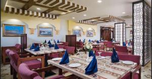 AL MANAF HOTEL SUITES في مسقط: مطعم عليه طاولات وكراسي عليها مناديل زرقاء