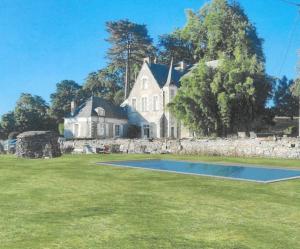 une grande maison blanche avec un terrain de basket dans la cour dans l'établissement Magnifique château au bord de la Mayenne 18 couchages, 