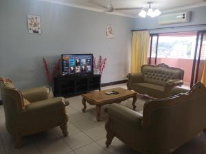 sala de estar con sofás, mesa y TV en Penthouse Marina Court Kk City, en Kota Kinabalu