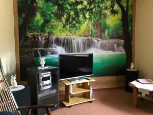 un soggiorno con TV e un dipinto di una cascata di Ferienwohnung 3 vom Friesenhof Wieratal 