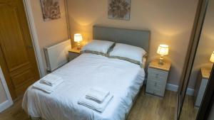 a bedroom with a white bed with two night stands at Plas Bach in Swansea