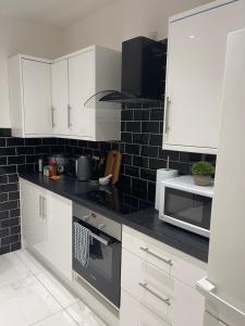 eine Küche mit weißen Schränken und einer Mikrowelle in der Unterkunft 2 Bedroom House next to Slade Green Station in Slades Green