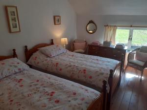 a bedroom with two beds and a dresser and a window at Beautiful 300 year old traditional country cottage in Courtmatrix