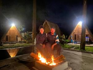 a man and a woman sitting around a bonfire at Triangle House and hot spring in Kintamani
