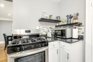 a kitchen with white cabinets and a stove top oven at Stylish, Tranquil & Comfy ~ Queen Beds ~ Pkg in Detroit