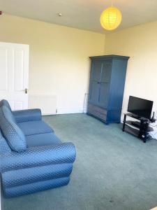 a living room with a blue couch and a tv at Sedgefield in Huddersfield