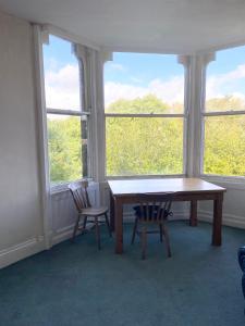 - une table et deux chaises dans une chambre avec fenêtres dans l'établissement Sedgefield, à Huddersfield