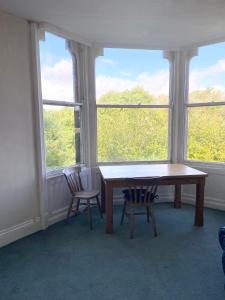 a table and two chairs in a room with windows at Sedgefield in Huddersfield