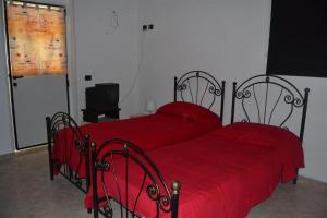 2 camas con colchas rojas en un dormitorio en B&B La tarentilla, en Lizzano