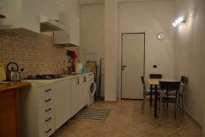 cocina con mesa y cocina con armarios blancos en B&B La tarentilla, en Lizzano