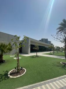 ドバイにあるMAG 565, Boulevard, Dubai South, Dubaiの草原二本の木がある建物
