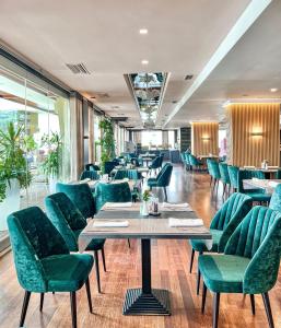 ein Restaurant mit grünen Stühlen und Tischen in der Unterkunft Tirana International Hotel & Conference Center in Tirana