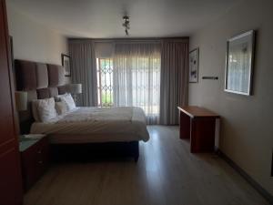 Un dormitorio con una cama grande y una ventana. en Mount Royal 02 Large 3 bedroom Ground floor apartment with Garden, en Johannesburgo