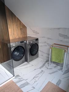 uma lavandaria com uma máquina de lavar roupa e uma toalha verde em APARTAMENT SZMARAGD em Zastań