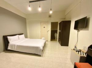 um quarto com uma cama e uma televisão de ecrã plano em Uh Hostel em Bangsaen