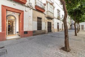 a tree on a cobblestone street next to a building at Allo Apartments Francos III Parking Centro 1 Habitación in Jerez de la Frontera