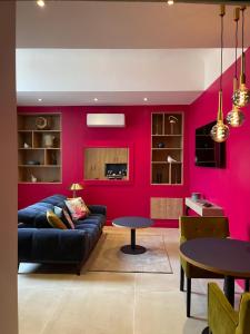 - un salon avec un canapé et un mur rose dans l'établissement Suite avec Spa Quartier Cathédrale, à Autun