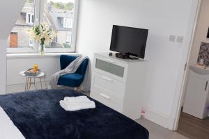 1 dormitorio con cama y vestidor con TV en Vion Apartment - King Suites, en Aberdeen