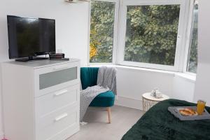 a bedroom with a tv and a bed and two windows at Vion Apartment - King Suites in Aberdeen