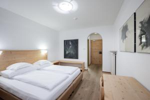 um quarto com uma grande cama branca e uma mesa em Rooms Kronblick em San Lorenzo di Sebato