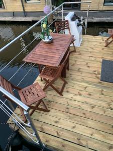 a wooden deck with a table and chairs on a boat at Unique new houseboat moored 4 in Zwartsluis