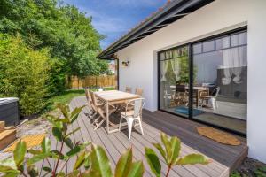 a wooden deck with a table and chairs at MAISON SWANNEL - Cosy & Spa in Andernos-les-Bains