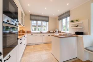 a kitchen with white cabinets and white appliances at Caras Hus in Midlum