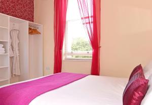 Schlafzimmer mit einem Bett mit roten Vorhängen und einem Fenster in der Unterkunft Cavendish apartment - central and spacious in Eastbourne