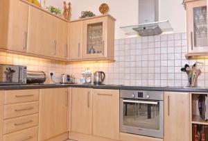 eine Küche mit Holzschränken und Küchengeräten aus Edelstahl in der Unterkunft Cavendish apartment - central and spacious in Eastbourne