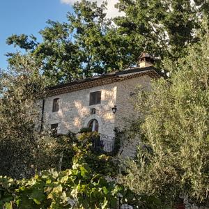 un vieux bâtiment en pierre avec des arbres devant lui dans l'établissement B&B Casal Cominium, à San Donato Val di Comino