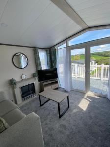 a living room with a couch and a tv and a fireplace at Riverwood Lodge in Porth