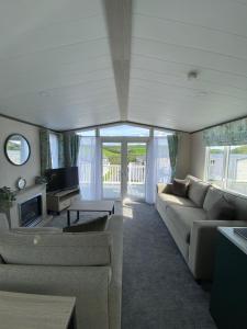 a living room with a couch and a tv at Riverwood Lodge in Porth