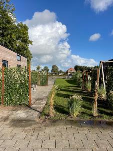 een tuin met een bakstenen pad en een hek bij Tiny House Indy-Blue in Giethoorn