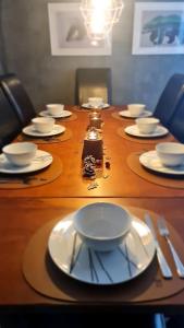 a long wooden table with plates and silverware on it at Arctic Lodge Tromvik with jacuzzi in Tromsø