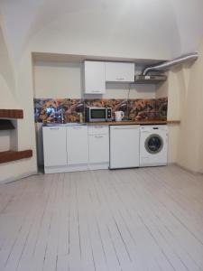 a kitchen with white cabinets and a washing machine at Vilnius Collegium Apartment in Vilnius