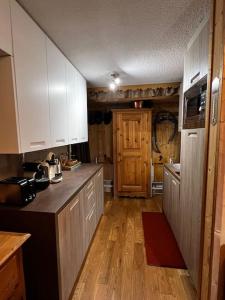 a kitchen with white cabinets and a wooden floor at Appartement la Clusaz avec terrasse sur les pistes de ski in Manigod