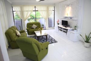 uma sala de estar com duas cadeiras verdes e uma mesa em Isabella Villa George Town Penang em George Town