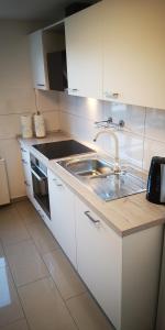 a white kitchen with a sink and a stove at SLEEP WELL Apartments, FEWO Falkenburg in Detmold