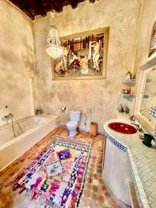 a bathroom with a tub and a toilet and a rug at Riad De La Mer in Essaouira
