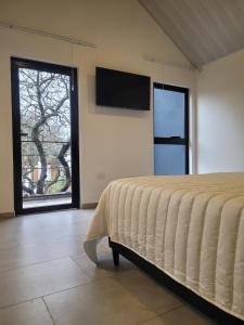 a bedroom with a bed and a tv on the wall at Laurentino Loft & Home in Villa General Belgrano
