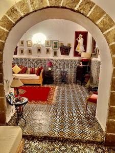 a living room with an archway with a couch and a table at Riad De La Mer in Essaouira
