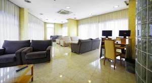 a living room with couches and a table with a desk at Hotel Florida in Arteixo