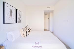 a bedroom with a white bed with two pillows on it at weforyou Las Nereidas de Los Álamos 3 bedrooms and PARKING in Torremolinos