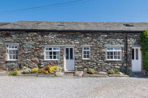Ce cottage en pierre dispose de portes et de fenêtres blanches. dans l'établissement Cottage 2, Old Farmhouse Mews, à Braithwaite