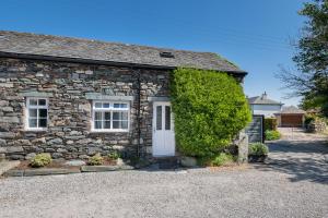 a stone cottage with a white door and windows at Cottage 1, Old Farmhouse Mews in Braithwaite