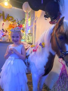 a little girl in a dress next to a fake pony at The Stable Annexe with hot tub & horses in Dogdyke +38 photos